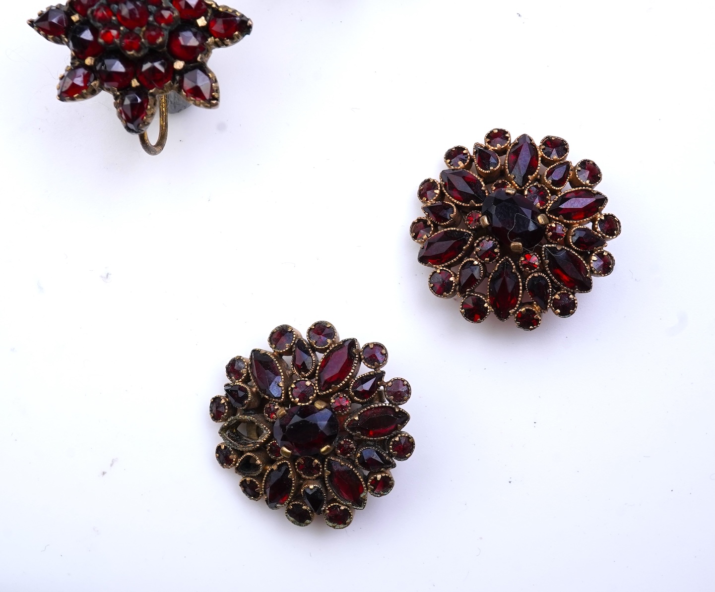 A suite of garnet and paste jewellery, comprising: a brooch, 5cm diameter; a bangle, inner circumference 16cm; two rings, sizes I and M; a pair of earrings, and a single earring, each set with rose-cut garnets; and a pai